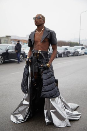 Téléchargez les photos : MILAN, ITALY - JANUARY 15, 2023: Man with long silver skirt and black leather shorts and shirt before Prada fashion show, Milan Fashion Week street style - en image libre de droit