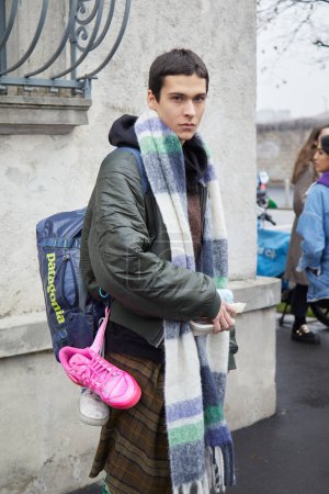 Photo for MILAN, ITALY - JANUARY 15, 2023: Man with Patagonia bag and pink and white Adidas sneakers before Prada fashion show, Milan Fashion Week street style - Royalty Free Image
