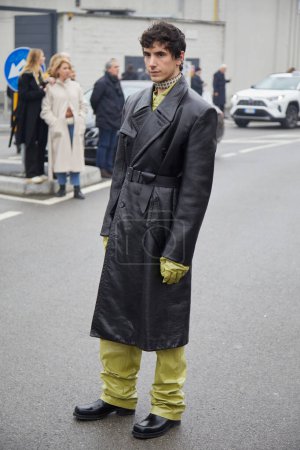 Foto de MILAN, ITALY - JANUARY 15, 2023: Man with black leather coat and acid green trousers before Prada fashion show, Milan Fashion Week street style - Imagen libre de derechos