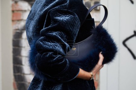 Photo for MILAN, ITALY - FEBRUARY 22, 2023: Woman with blue velvet Fendi jacket and leather bag with fur before Fendi fashion show, Milan Fashion Week street style - Royalty Free Image