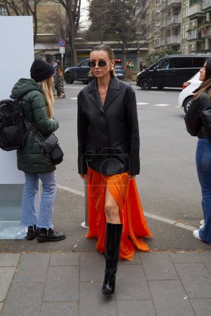 Téléchargez les photos : MILAN, ITALIE - 22 FÉVRIER 2023 : Nataly Osmann avec jupe orange et veste noire avant le défilé de mode Alberta Ferretti, Milan Fashion Week street style - en image libre de droit