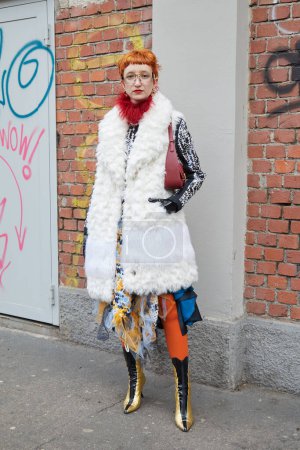 Foto de MILÁN, ITALIA - 22 DE FEBRERO DE 2023: Mujer con abrigo de piel blanca y botas doradas y negras antes del desfile de moda Fendi, Milan Fashion Week street style - Imagen libre de derechos