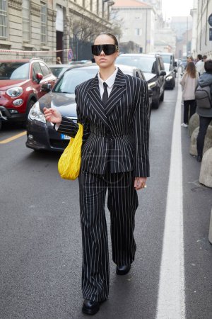 Téléchargez les photos : MILAN, ITALIE - 23 FÉVRIER 2023 : Femme avec veste et pantalon à rayures avant le défilé de mode Genny, Milan Fashion Week street style - en image libre de droit