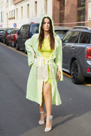 Téléchargez les photos : MILAN, ITALIE - 23 FÉVRIER 2023 : Femme avec robe verte et veste avec capuche avant le défilé de mode Genny, Milan Fashion Week street style - en image libre de droit