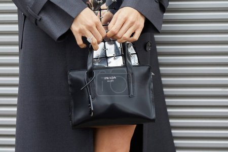 Téléchargez les photos : MILAN, ITALIE - 23 FÉVRIER 2023 : Femme avec sac Prada en cuir noir et robe argentée avant le défilé Prada, Milan Fashion Week street style - en image libre de droit