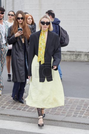 Photo for MILAN, ITALY - FEBRUARY 23, 2023: Woman with yellow skirt and black jacket before Prada fashion show, Milan Fashion Week street style - Royalty Free Image