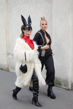 Téléchargez les photos : MILAN, ITALIE - 23 FÉVRIER 2023 : Femmes avec manteau en fourrure blanche, bottes en cuir noir et masque de lapin avant le défilé Prada, Milan Fashion Week street style - en image libre de droit