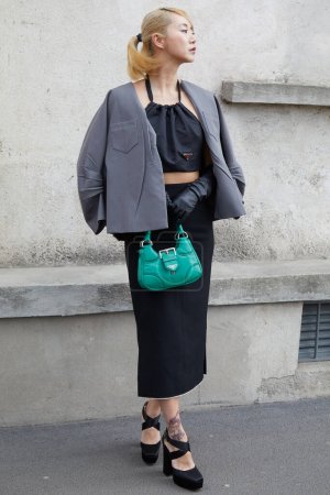 Foto de MILÁN, ITALIA - 23 DE FEBRERO DE 2023: Mujer con chaqueta gris y bolso de cuero verde antes del desfile de moda Prada, Milan Fashion Week street style - Imagen libre de derechos
