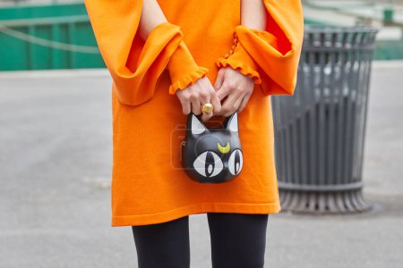 Téléchargez les photos : MILAN, ITALIE - 24 FÉVRIER 2023 : Femme avec robe orange et sac avec chat et demi-lune avant le défilé Sportmax, Milan Fashion Week street style - en image libre de droit