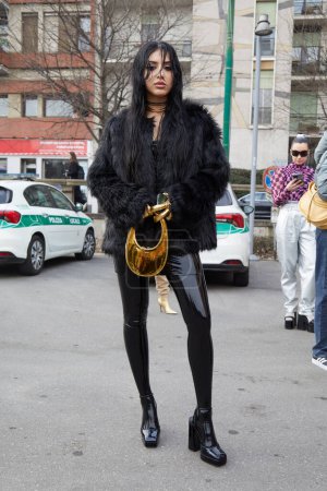 Téléchargez les photos : MILAN, ITALIE - 24 FÉVRIER 2023 : Femme avec bas et jupe en latex noir et sac et gants Coperni dorés avant le défilé Sportmax, Milan Fashion Week street style - en image libre de droit