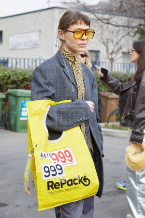 Foto de MILÁN, ITALIA - 24 DE FEBRERO DE 2023: Mujer con bolso Repack amarillo, chaqueta gris y corbata antes del desfile de moda Sportmax, Milan Fashion Week street style - Imagen libre de derechos