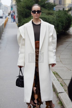 Téléchargez les photos : MILAN, ITALIE - 24 FÉVRIER 2023 : Femme avec manteau blanc et lunettes de soleil noires avant Philosophie par Lorenzo Serafini défilé de mode, Milan Fashion Week street style - en image libre de droit