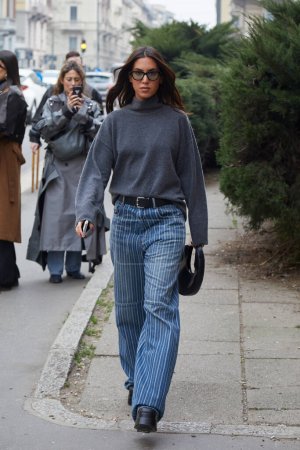 Photo for MILAN, ITALY - FEBRUARY 24, 2023: Woman with grey wool turtleneck and blue striped denim trousers before Philosophy by Lorenzo Serafini fashion show, Milan Fashion Week street style - Royalty Free Image