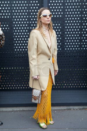 Téléchargez les photos : MILAN, ITALIE - 24 FÉVRIER 2023 : Femme avec veste beige, sac Gucci et jupe filet orange avant le défilé Gucci, Milan Fashion Week street style - en image libre de droit