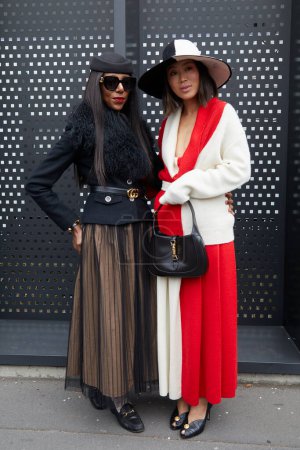 Téléchargez les photos : MILAN, ITALIE - 24 FÉVRIER 2023 : Femmes avec veste noire et veste rouge et blanche et jupe avant le défilé Gucci, Milan Fashion Week street style - en image libre de droit