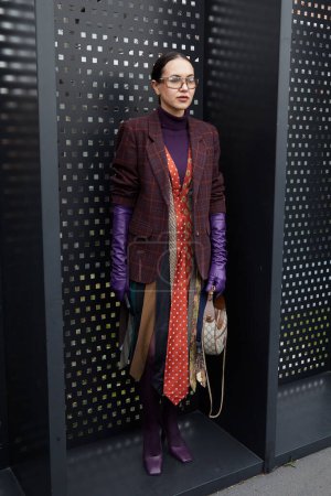 Téléchargez les photos : MILAN, ITALIE - 24 FÉVRIER 2023 : Femme avec des gants en cuir violet et robe faite de cravates avant le défilé de mode Gucci, Milan Fashion Week street style - en image libre de droit