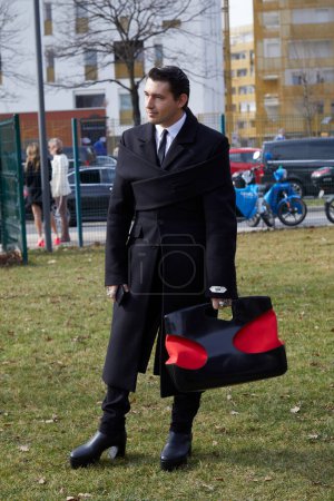 Photo for MILAN, ITALY - FEBRUARY 25, 2023: Man with Gmbh Demi Couture black coat before Ferragamo fashion show, Milan Fashion Week street style - Royalty Free Image