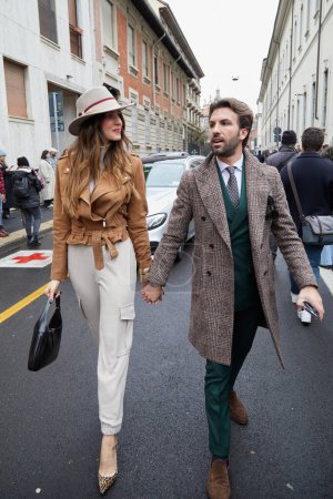 Téléchargez les photos : MILAN, ITALIE - 26 FÉVRIER 2023 : Femme et homme avec veste en daim marron et costume vert avant le défilé de mode Luisa Spagnoli, Milan Fashion Week street style - en image libre de droit