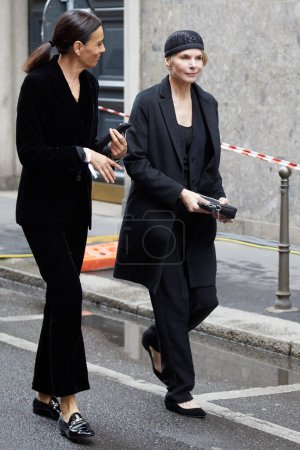 Photo for MILAN, ITALY - FEBRUARY 26, 2023: Women with black jacket and trousers before Giorgio Armani fashion show, Milan Fashion Week street style - Royalty Free Image