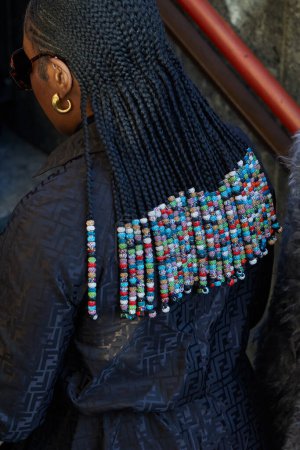 Téléchargez les photos : MILAN, ITALIE - 13 JANVIER 2024 : Femme avec des tresses avec des perles et une veste à motif logo Fendi noir avant le défilé MSGM, Milan Fashion Week street style - en image libre de droit
