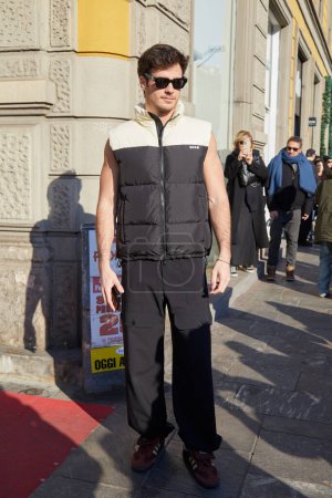 Téléchargez les photos : MILAN, ITALIE - 13 JANVIER 2024 : Homme avec MSGM veste sans manches noir et blanc et pantalon cargo noir avant le défilé de mode MSGM, Milan Fashion Week street style - en image libre de droit