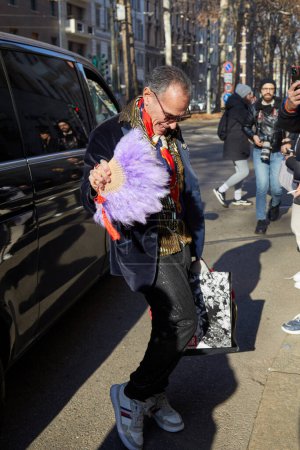 Photo for MILAN, ITALY - JANUARY 13, 2024: Man with purple feathers fan and blue velvet jacket before Dolce and Gabbana fashion show, Milan Fashion Week street style - Royalty Free Image