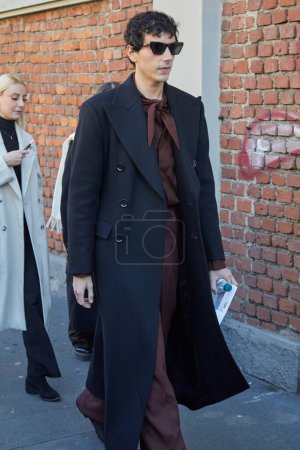 Téléchargez les photos : MILAN, ITALIE - 13 JANVIER 2024 : Homme avec manteau noir et chemise et pantalon marron avant le défilé de mode Fendi, Milan Fashion Week street style - en image libre de droit