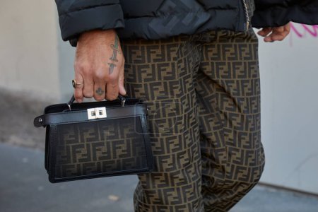 Téléchargez les photos : MILAN, ITALIE - 13 JANVIER 2024 : Homme avec sac Fendi et pantalon à motifs marron avant le défilé Fendi, Milan Fashion Week street style - en image libre de droit