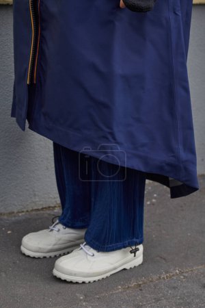Photo for MILAN, ITALY - JANUARY 14, 2024: Man with blue raincoat, trousers and white boots before K-Way fashion show, Milan Fashion Week street style - Royalty Free Image
