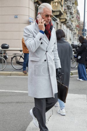 Foto de MILÁN, ITALIA - 14 DE ENERO DE 2024: Hombre con chaqueta gris claro y pantalones de rayas antes del desfile de moda K-Way, Milan Fashion Week street style - Imagen libre de derechos