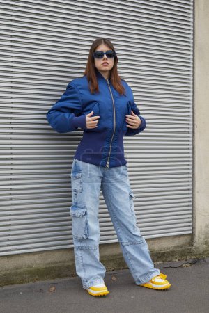 Photo for MILAN, ITALY - JANUARY 14, 2024: Woman with blue bomber jacket and denim cargo trousers before Prada fashion show, Milan Fashion Week street style - Royalty Free Image