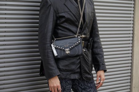 Foto de MILÁN, ITALIA - 14 DE ENERO DE 2024: Hombre con bolso Prada con tacos y chaqueta de cuero negro antes del desfile de moda Prada, Milan Fashion Week street style - Imagen libre de derechos