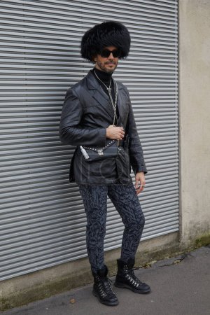 Téléchargez les photos : MILAN, ITALIE - 14 JANVIER 2024 : Homme avec chapeau en fourrure noire, sac Prada en cuir noir et veste avant le défilé Prada, Milan Fashion Week street style - en image libre de droit