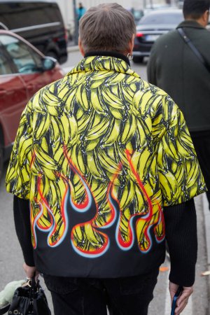Foto de MILÁN, ITALIA - 14 DE ENERO DE 2024: Hombre con chaqueta con diseño de plátano y llamas antes del desfile de moda Prada, Milan Fashion Week street style - Imagen libre de derechos