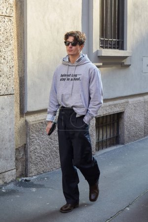 Téléchargez les photos : MILAN, ITALIE - 15 JANVIER 2024 : Homme avec sweat à capuche Helmut Lang gris et pantalon noir avant le défilé Giorgio Armani, Milan Fashion Week street style - en image libre de droit