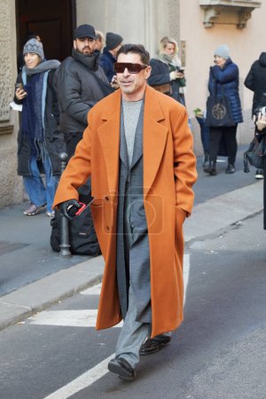 Foto de MILÁN, ITALIA - 15 DE ENERO DE 2024: Alex Badia con abrigo naranja y chaqueta gris y pantalones antes del desfile de Giorgio Armani, Milan Fashion Week street style - Imagen libre de derechos
