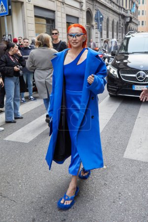 Foto de MILÁN, ITALIA - 21 DE FEBRERO DE 2024: Mujer con vestido azul, abrigo y pelo rojo antes del desfile de moda Iceberg, Milan Fashion Week street styl - Imagen libre de derechos