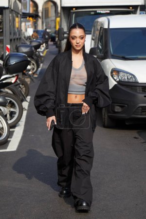 Photo for MILAN, ITALY - FEBRUARY 21 , 2024: Woman with black bomber jacket and trousers before Onitsuka Tiger fashion show, Milan Fashion Week street styl - Royalty Free Image