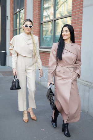Téléchargez les photos : MILAN, ITALIE - 21 FÉVRIER 2024 : Femmes avec chemise et pantalon beige et trench coat en cuir rose pâle avant le défilé Fendi, Milan Fashion Week street style - en image libre de droit