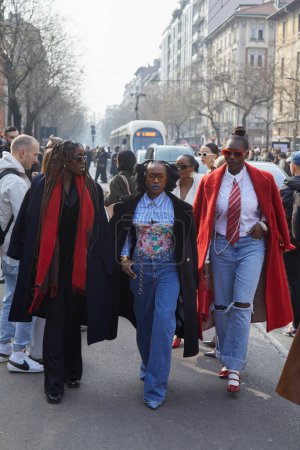 Téléchargez les photos : MILAN, ITALIE - 21 FÉVRIER 2024 : Femmes avec manteau noir, écharpe rouge et pantalon en denim avant le défilé Fendi, Milan Fashion Week street style - en image libre de droit