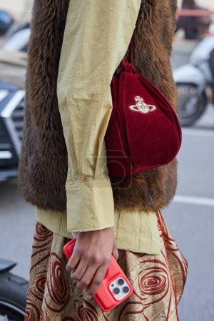 Photo for MILAN, ITALY - FEBRUARY 21 , 2024: Woman with red velvet Vivienne Westood bag before Marco Rambaldi fashion show, Milan Fashion Week street style - Royalty Free Image