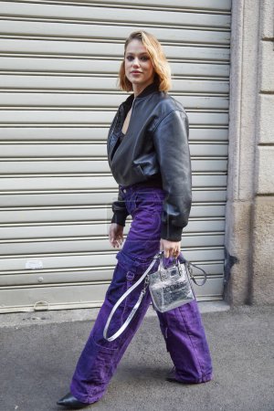 Photo for MILAN, ITALY - FEBRUARY 21 , 2024: Woman with black leather bomber jacket and purple cargo denim trousers before Iceberg fashion show, Milan Fashion Week street style - Royalty Free Image