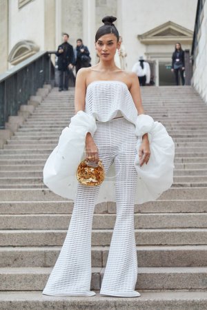 Foto de MILÁN, ITALIA - 22 DE FEBRERO DE 2024: Mujer con pantalones blancos y bolso de lentejuelas doradas antes del desfile de moda Genny, Milan Fashion Week street style - Imagen libre de derechos