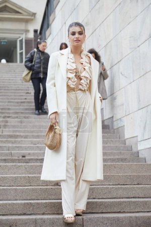 Téléchargez les photos : MILAN, ITALIE - 22 FEVRIER 2024 : Femme avec veste longue beige et pantalon avant le défilé de mode Genny, Milan Fashion Week street style - en image libre de droit