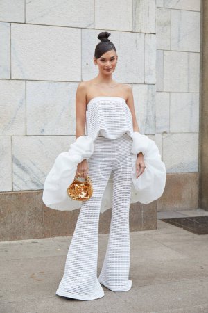 Téléchargez les photos : MILAN, ITALIE - 22 FÉVRIER 2024 : Femme avec pantalon blanc et sac à paillettes dorées avant le défilé de mode Genny, Milan Fashion Week street style - en image libre de droit