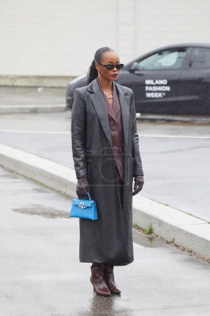 Téléchargez les photos : MILAN, ITALIE - 22 FÉVRIER 2024 : Femme avec manteau en cuir noir et sac bleu avant le défilé Prada, Milan Fashion Week street style - en image libre de droit