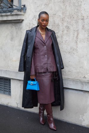 Foto de MILÁN, ITALIA - 22 DE FEBRERO DE 2024: Mujer con gabardina de cuero negro y chaqueta y falda de cuero color burdeos antes del desfile de moda Prada, Milan Fashion Week street style - Imagen libre de derechos