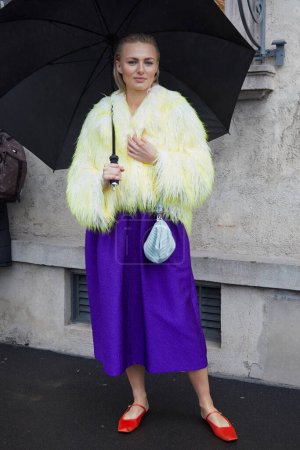 Photo for MILAN, ITALY - FEBRUARY 22, 2024: Woman with yellow fur coat and purple skirt before Prada fashion show, Milan Fashion Week street style - Royalty Free Image