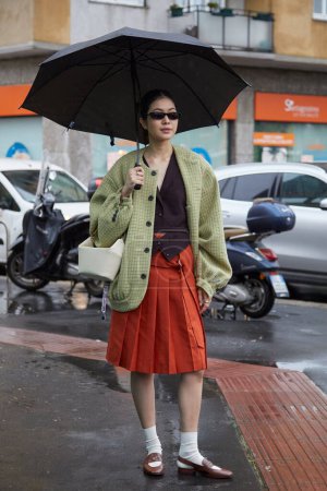 Téléchargez les photos : MILAN, ITALIE - 23 FÉVRIER 2024 : Femme avec jupe orange et veste jaune verte avant le défilé Tods, Milan Fashion Week street style - en image libre de droit