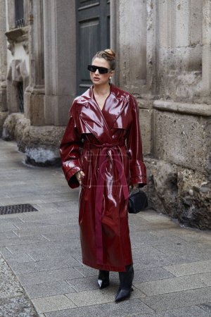 Foto de MILÁN, ITALIA - 23 DE FEBRERO DE 2024: Mujer con gabardina larga y brillante antes del desfile de moda Blumarine, Milan Fashion Week street style - Imagen libre de derechos